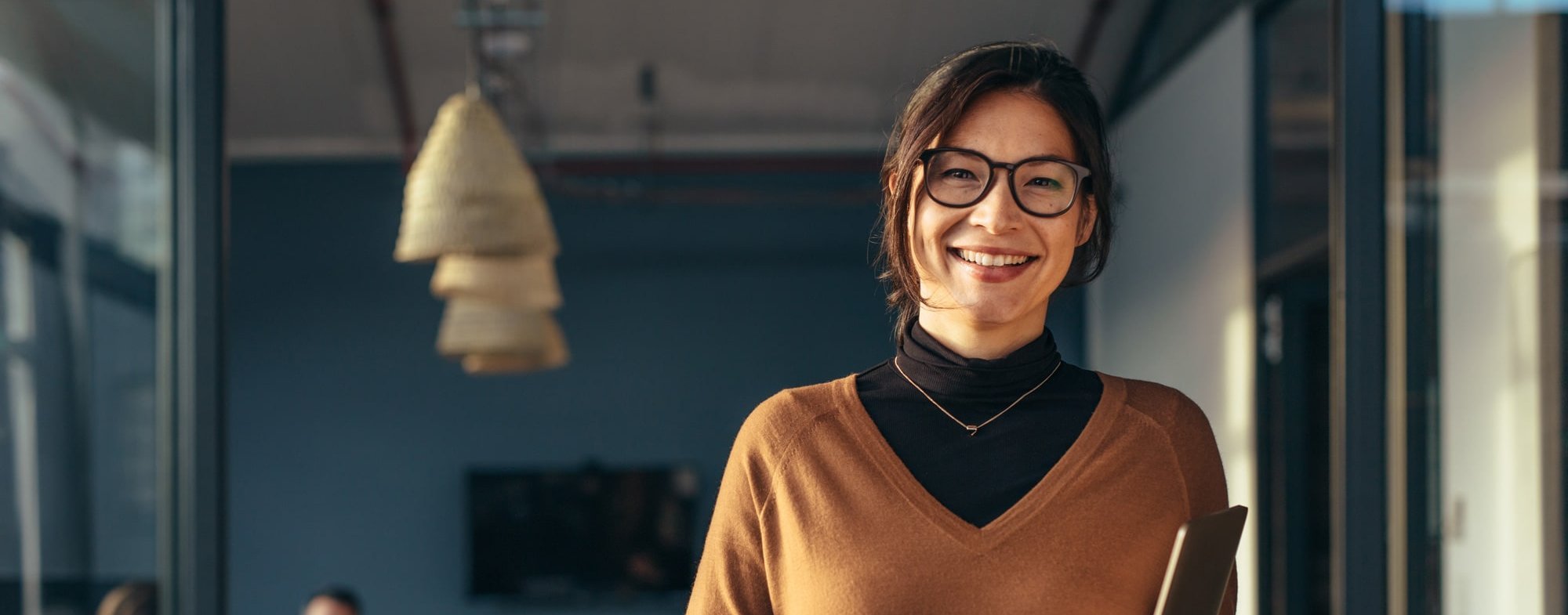 Lächelnde Frau mit Brille in einem modernen Büro.