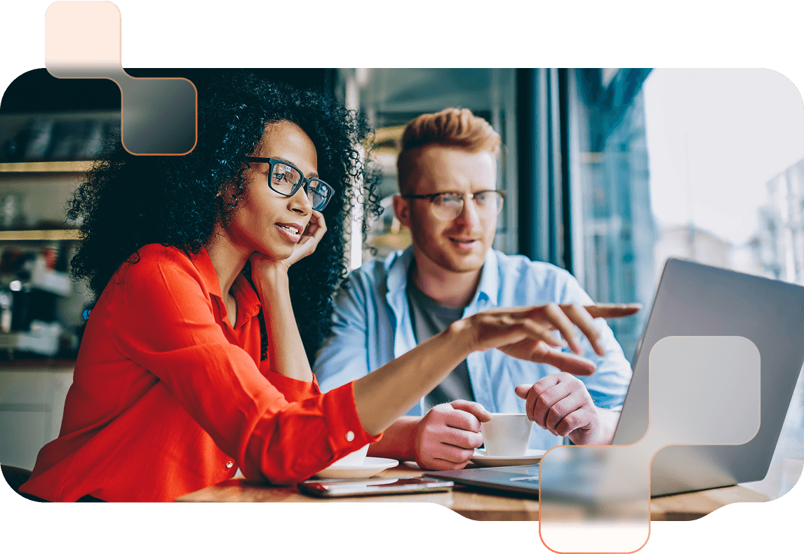 Arbeiten-BMD-Software Frau mit roter Bluse und Mann mit hellem Hemd sitzen vor Laptop, Frau zeigt auf den Bildschirm.