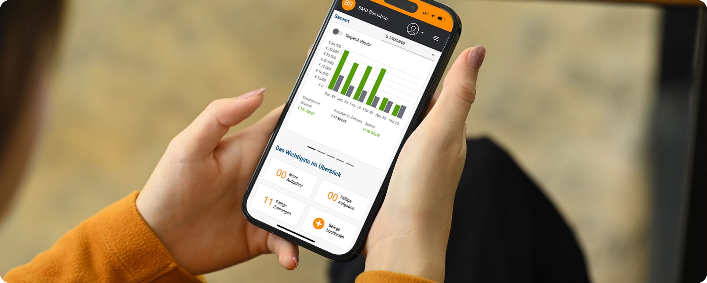 Hände einer Frau, die ein Smartphone hält mit Dashboard von my BMD Com. 