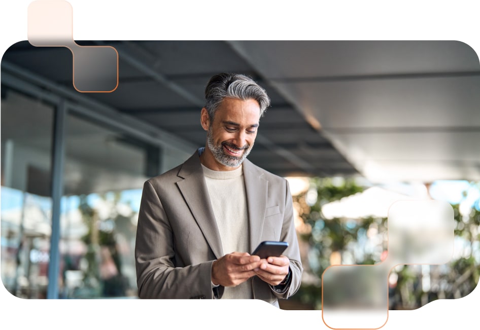 Ein lächelnder Mann im Business-Outfit steht draußen und nutzt sein Smartphone, umgeben von einer modernen Umgebung mit weichem Tageslicht.