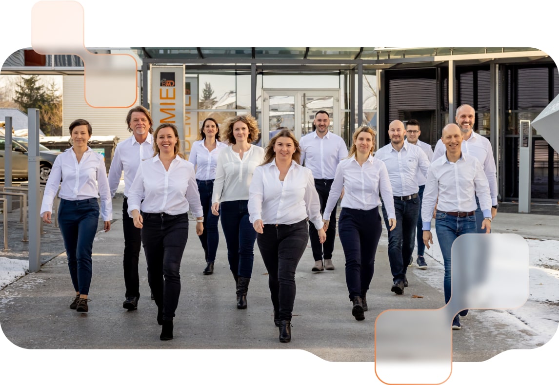 Das Team der BMD Projektbegleitung steht in einer Gruppe vor dem Firmengebäude, freundlich lächelnd und in einheitlicher Kleidung, bereit für gemeinsame Projekte.