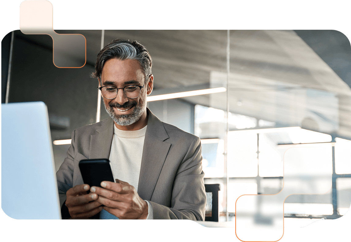 Teaser-BMDWeb-BMDGo Mann mit Brille blickt lächelnd auf sein Smartphone, vor ihm steht ein Laptop.