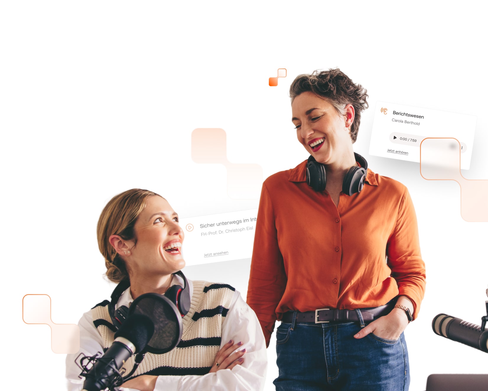 Zwei Frauen mit Kopfhörern um den Hals und vor Mikrofonen lächeln sich an. 