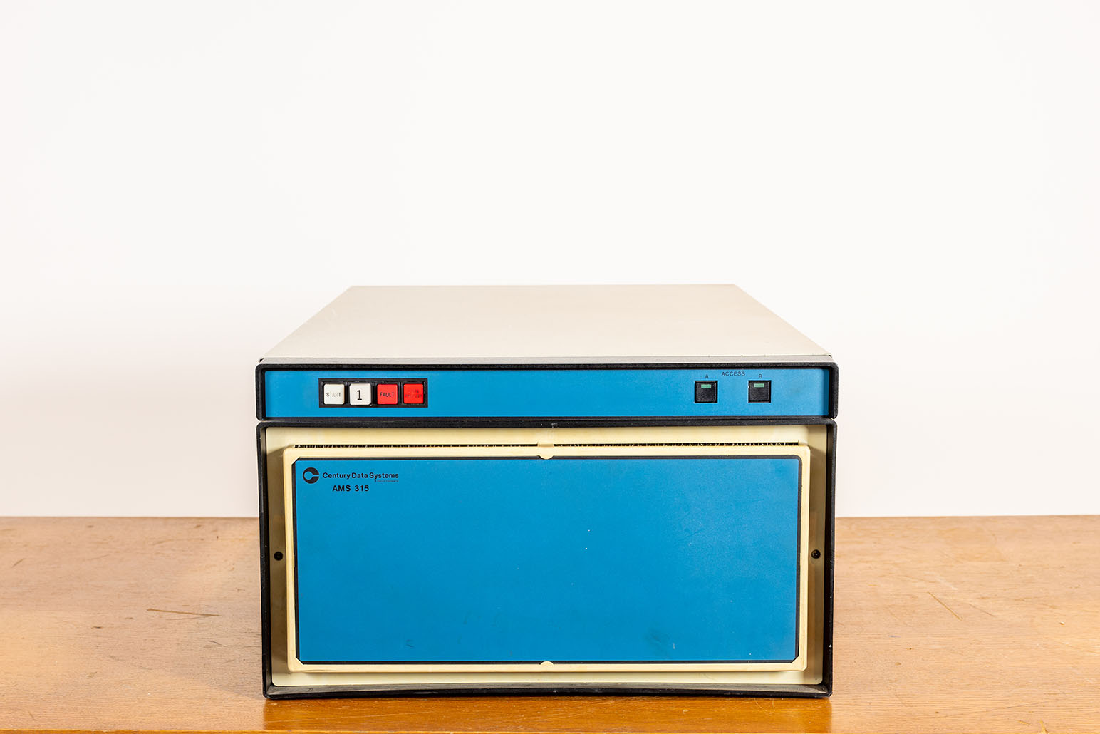 Kastenförmige Festplatte in blau-beige vor weißer Wand