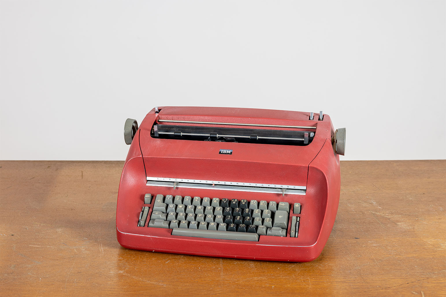 Rote Schreibmaschine mit grauen Tasten auf Holztisch