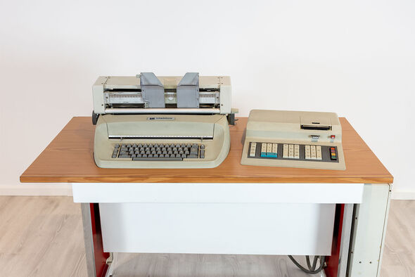 Zwei beige Rechenmaschinen auf Holztisch