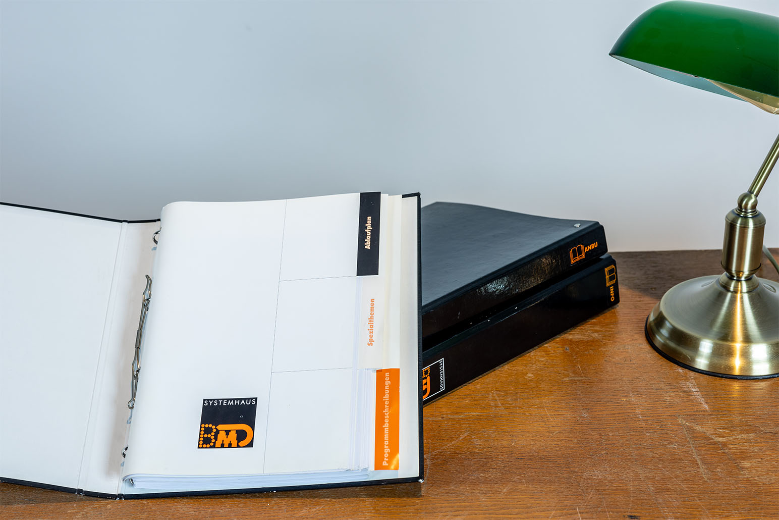 Geöffneter Ordner auf Holztisch mit grüner Lampe