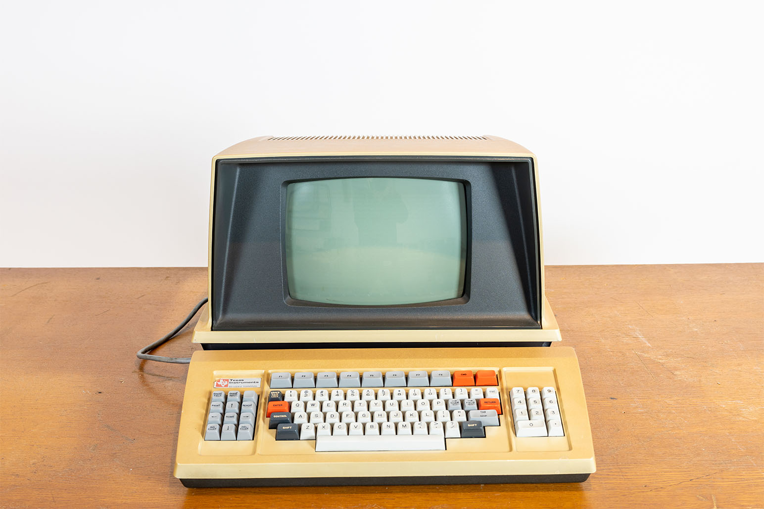 Beige-grauer Minicomputer mit weiß-grau-orangen Tasten auf Holztisch