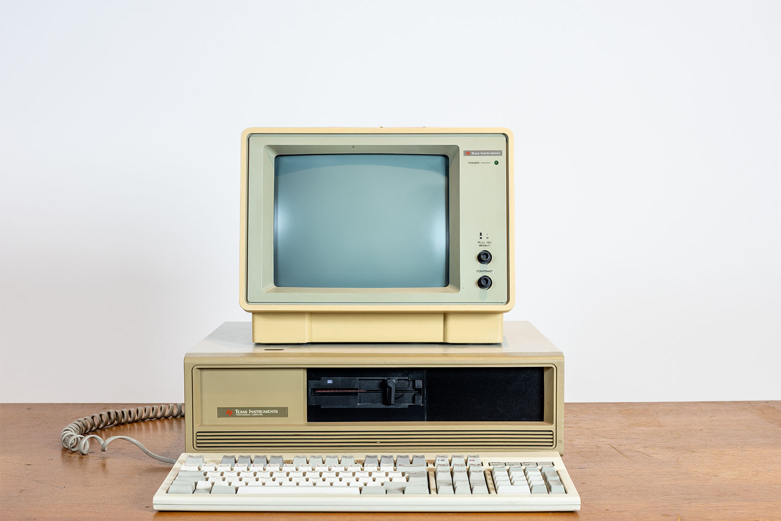 Beiger PC mit Bildschirm und mit weiß-grauer Tastatur auf Holztisch