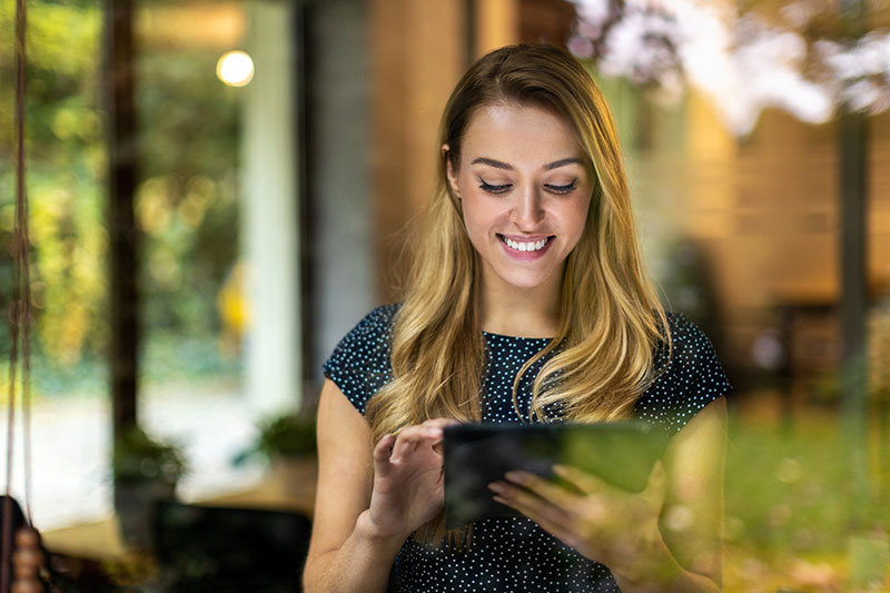 Das Bild zeigt eine junge Frau, die am Tablet arbeitet.