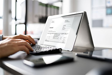 Hände tippen auf Tastatur und ein Bildschirm mit einer digitalen Rechnung.