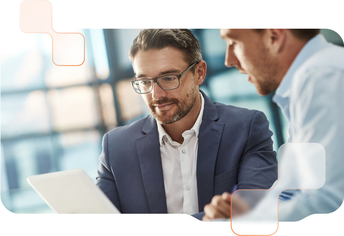BMD mit Valutico Zwei Männer im Business-Outfit sitzen fokussiert vor einem Tablet. Dahinter moderne Büro-Umgebung.