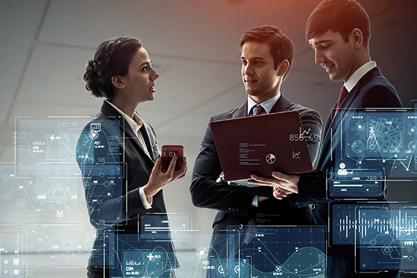 Egy nőt és két férfit látsz beszélgetni, a nő egy okostelefont, a férfi pedig egy laptopot tart a kezében. Az előtérben különböző grafikák jelennek meg