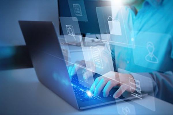 A képen egy férfi látható, amint egy laptop billentyűzetén gépel, miközben ikonok lebegnek a levegőben.