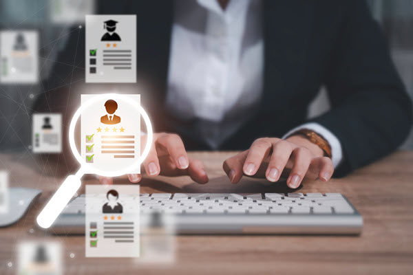 A képen egy billentyűzeten gépelő nő látható, előtérben egy nagyítóval.